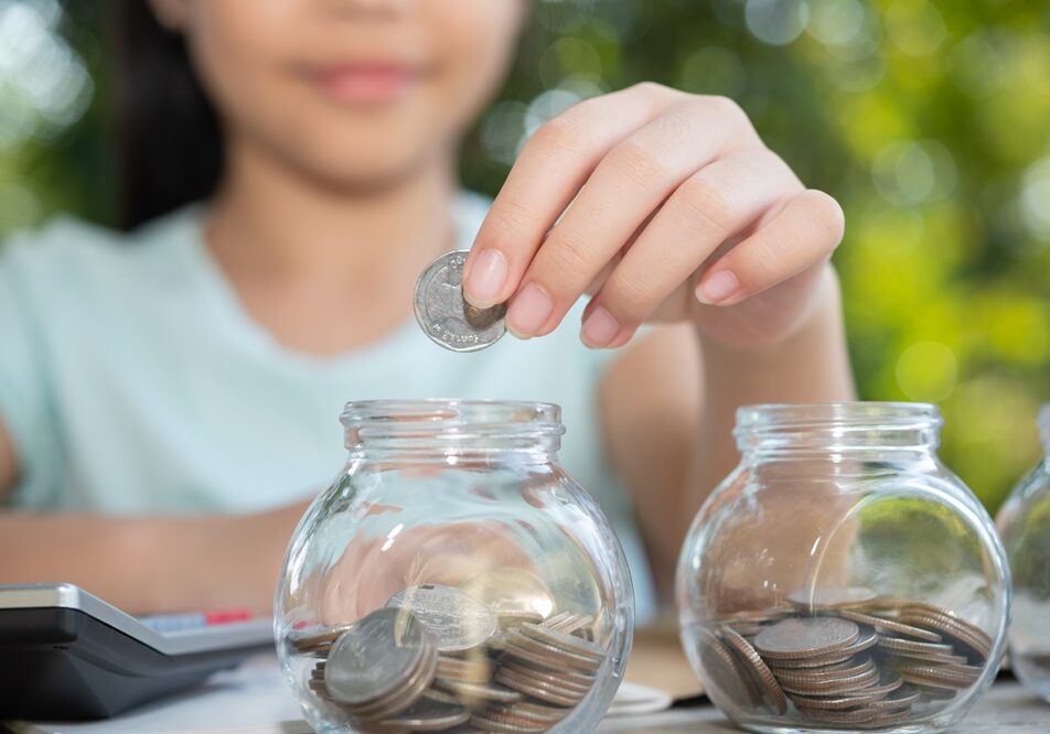 1742360373-cute-asian-little-girl-playing-with-coins-making-stacks-money-kid-saving-money-into-piggy-bank-into-glass-jar-child-counting-his-saved-coins-children-learning-about-future-concept.jpg